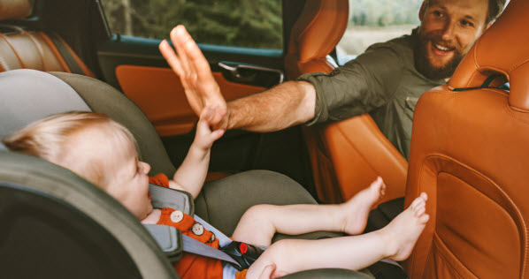 father in car with infant sitting in car seat